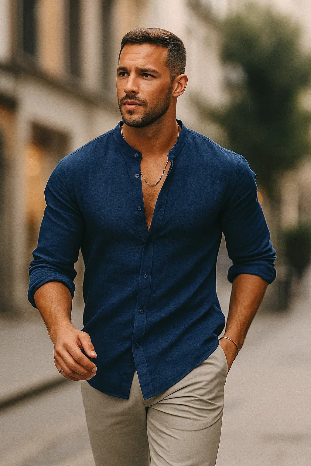 Man wearing a navy blue Zion men's band collar button-up shirt with long sleeves rolled up, paired with light pants.