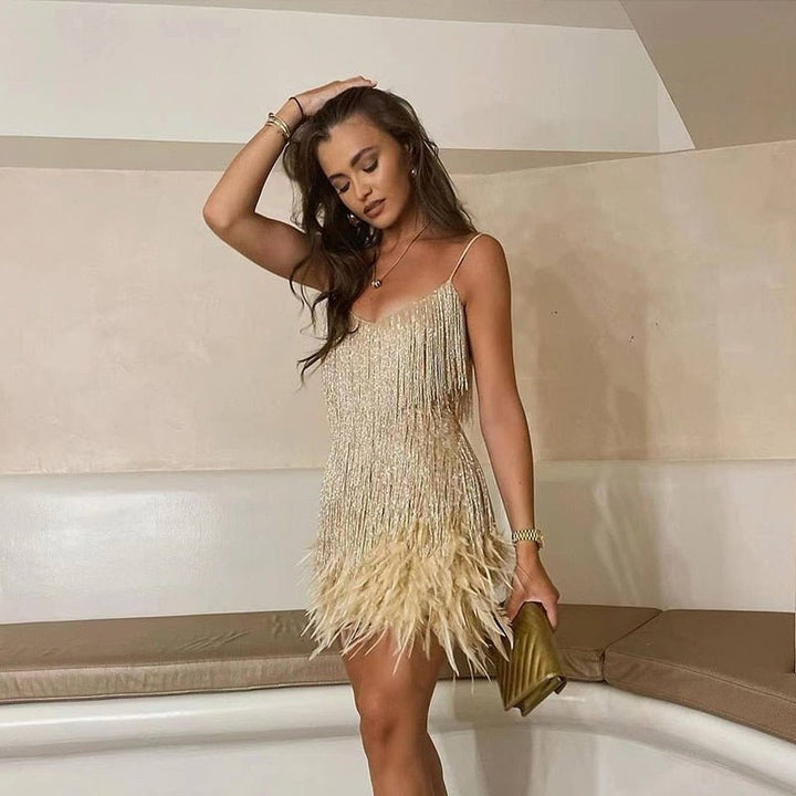 Woman in a gold sequin mini dress with fringe and feathers holding a clutch.