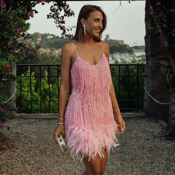 Pink sequin fringe mini dress with feather hem on a woman outdoors.